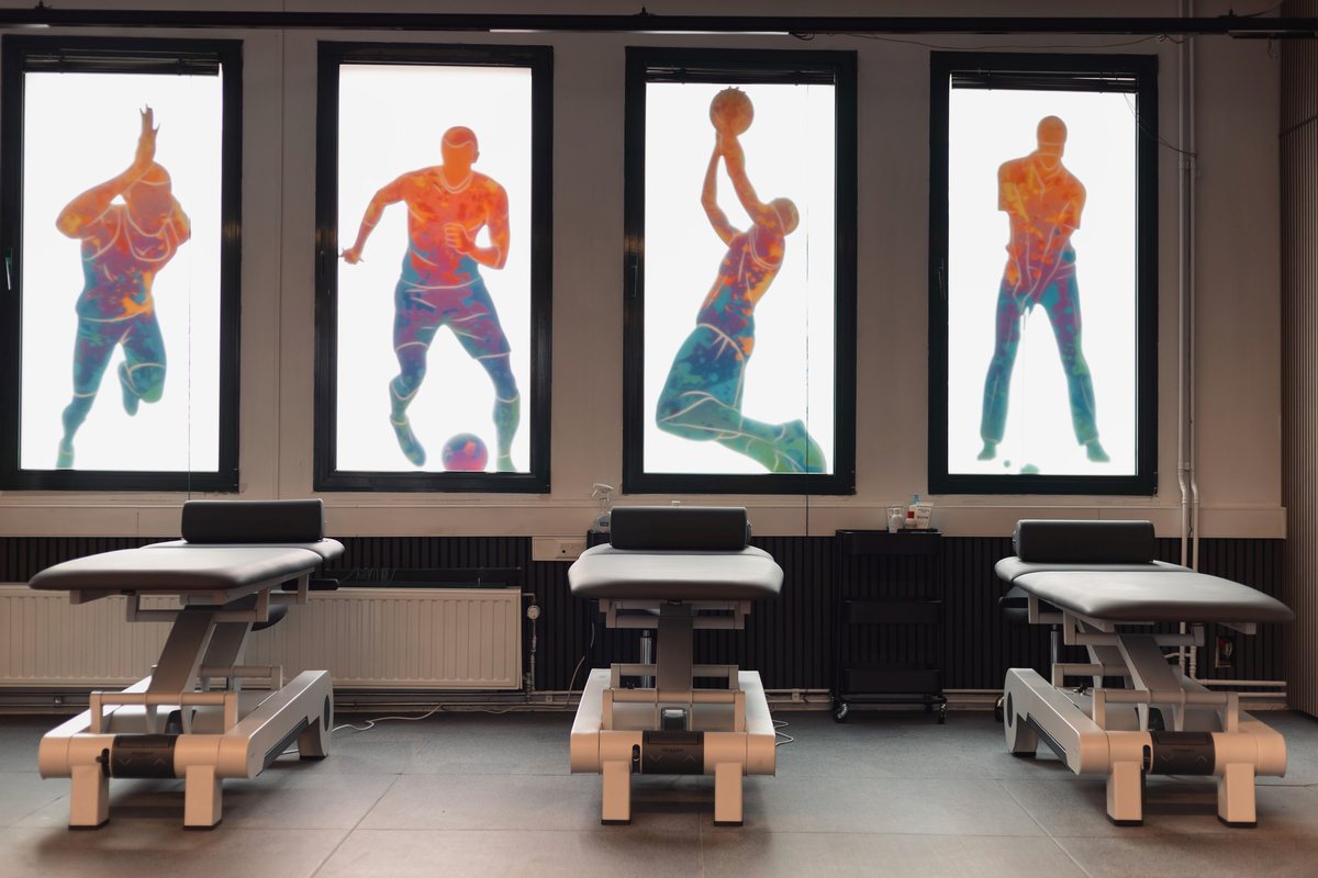 Salle de rééducation avec tables de kinésithérapie et panneaux d’anatomie rétroéclairés