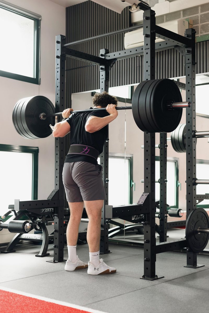 Athlète en squat sous barre dans la cage de force
